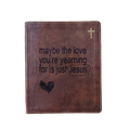 A brown faux-leather Bible cover or journal with a gold cross in the top right corner and the printed phrase 'maybe the love you're yearning for is just Jesus' with a heart and underline graphic on the front, shown on a plain white background.