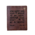 A brown leather Bible cover featuring black embossed text from Psalm 119:103 and a small gold cross in the top right corner, shown against a plain white background.