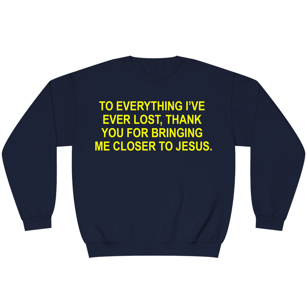 A navy blue crewneck sweatshirt with bold yellow text on the chest that reads, 'TO EVERYTHING I'VE EVER LOST, THANK YOU FOR BRINGING ME CLOSER TO JESUS.'.
