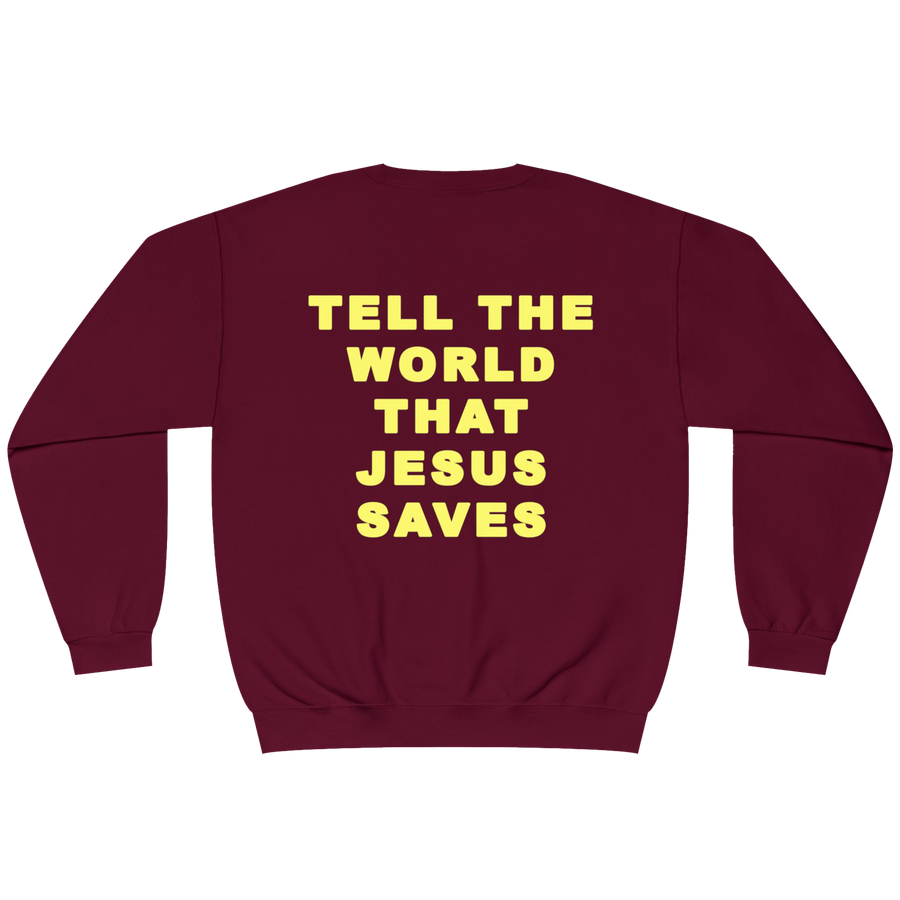 A maroon crewneck sweatshirt with the phrase 'TELL THE WORLD THAT JESUS SAVES' printed in bold yellow capital letters on the back, shown against a plain white background.