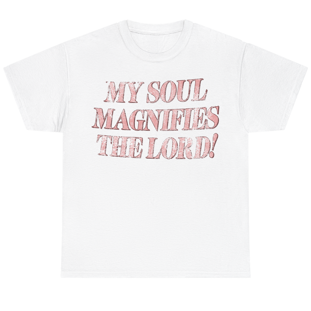 A white short-sleeve crewneck t-shirt featuring the text 'MY SOUL MAGNIFIES THE LORD!' printed on the chest in a textured, distressed pink font.