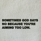 Black distressed text reading 'SOMETIMES GOD SAYS NO BECAUSE YOU'RE AIMING TOO LOW.' printed on a light beige textured fabric background.
