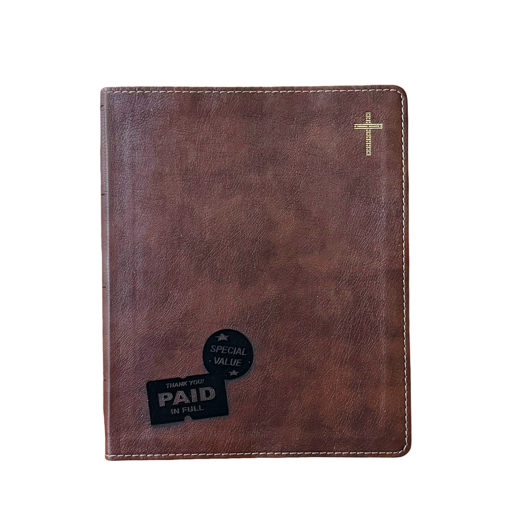 A brown faux-leather Bible cover with white contrast stitching, a small gold cross on the top right, and two black promotional stickers on the bottom left, shown against a plain white background.