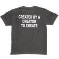 A dark gray washed t-shirt shown from the back, featuring the phrase 'CREATED BY A CREATOR TO CREATE' printed in bold white capital letters across the upper back.
