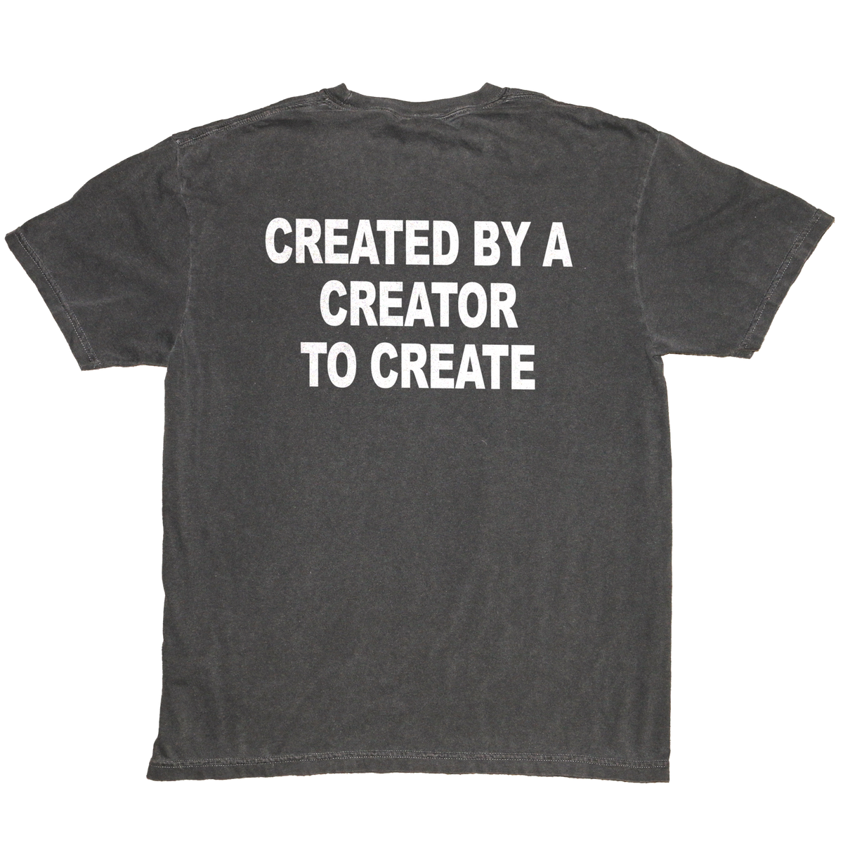 A dark gray washed t-shirt shown from the back, featuring the phrase 'CREATED BY A CREATOR TO CREATE' printed in bold white capital letters across the upper back.