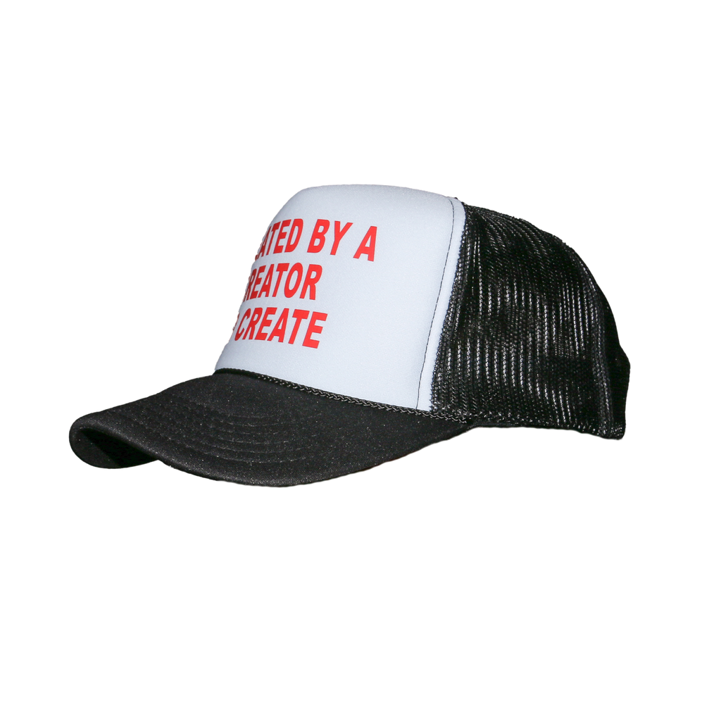 A black and white trucker hat with red text on the front panel reading 'CREATED BY A CREATOR TO CREATE'.