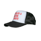 A black and white trucker hat with red text on the front panel reading 'CREATED BY A CREATOR TO CREATE'.