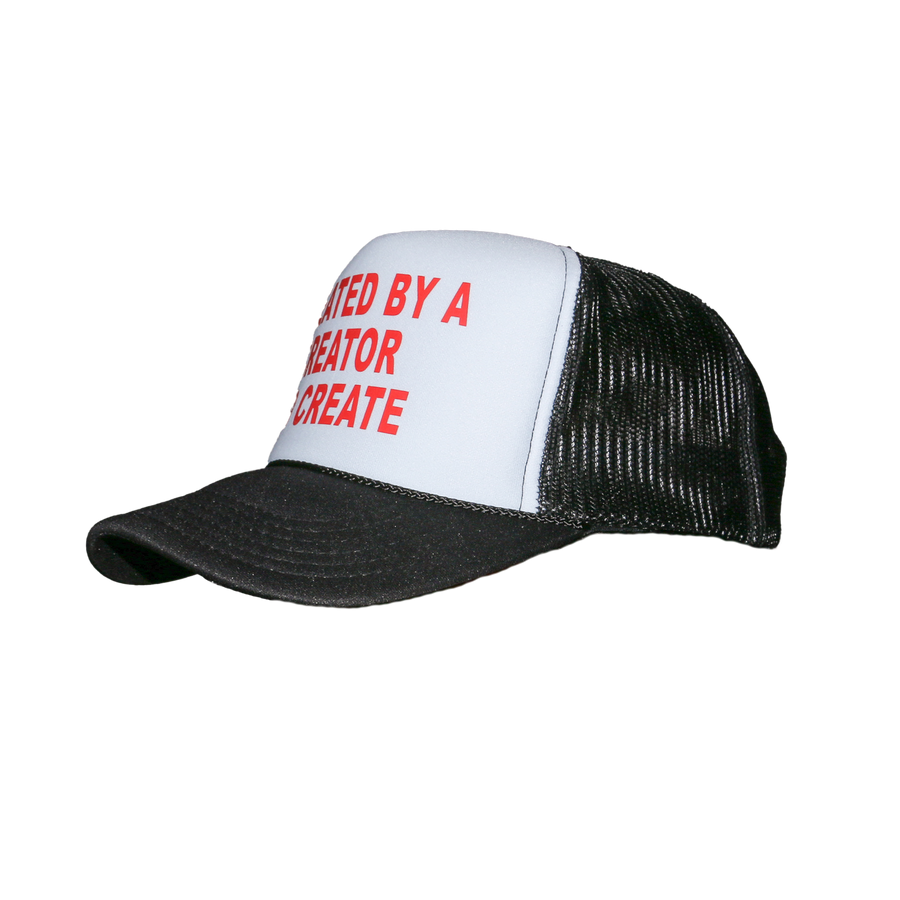 A black and white trucker hat with red text on the front panel reading 'CREATED BY A CREATOR TO CREATE'.