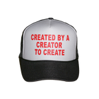 A black and white trucker hat with red text on the front panel that reads 'CREATED BY A CREATOR TO CREATE'.