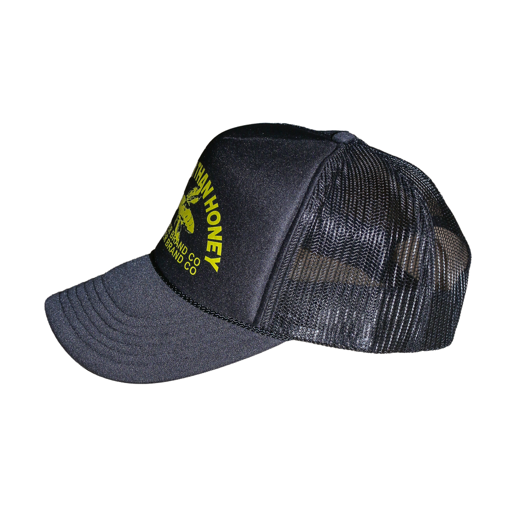 A dark gray and black trucker hat with a yellow embroidered logo on the front panel, featuring a curved brim and mesh back.