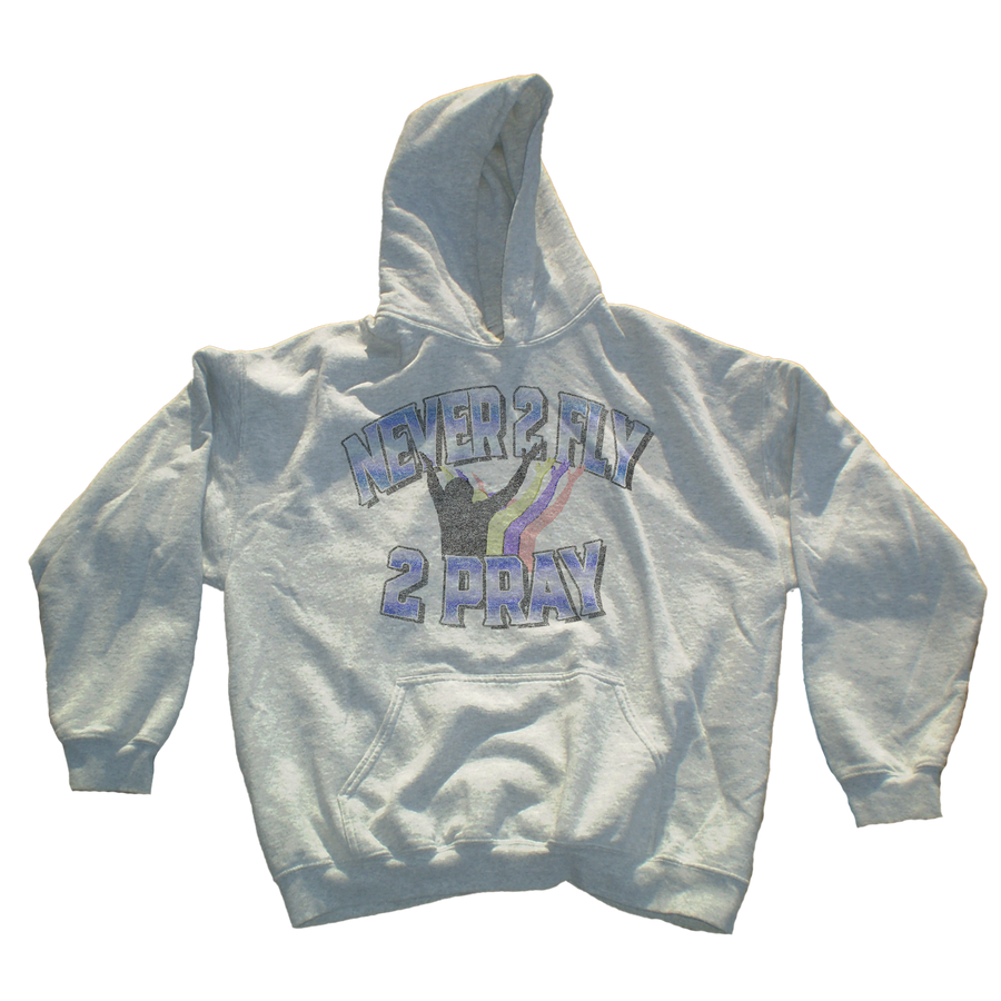 A light gray heather pullover hoodie featuring a front graphic with the text 'NEVER 2 FLY 2 PRAY' in blue and purple outlined lettering, with a black silhouette of a person praying and a small rainbow accent.