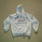 A light gray hooded sweatshirt laid flat on a textured concrete surface, featuring a distressed graphic on the chest that reads 'JESUS UNLAWED ATHLETIC DEPT' in blue and red.